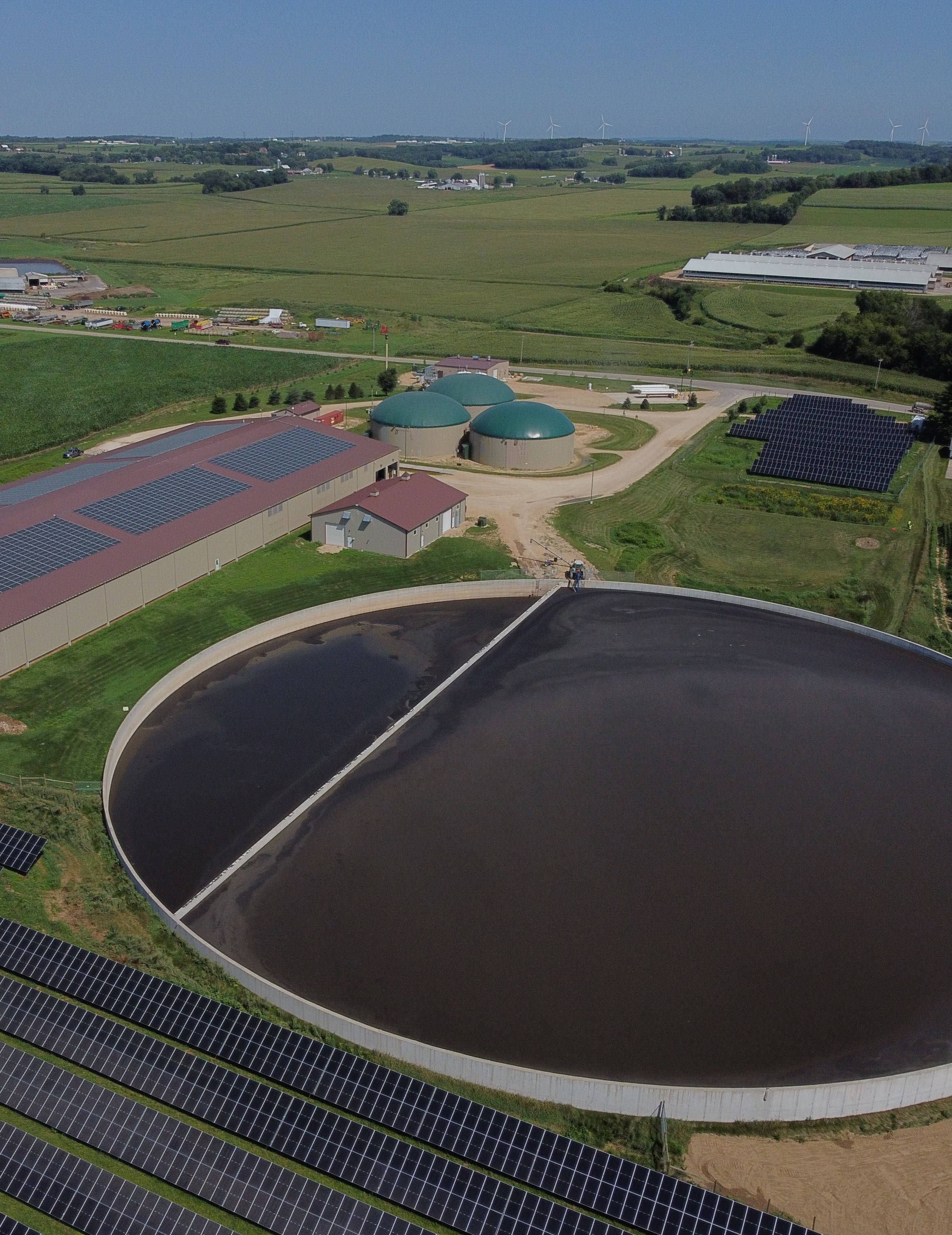 Oblique aerial image of farmland, with solar panels and manure facilities in the foreground.